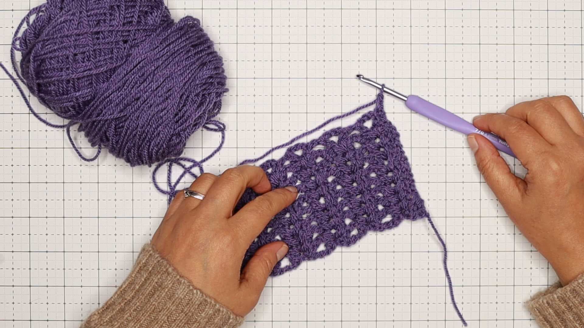 Beth is introducing crochet hook handling on top of a cutting mat with the hook attached to the pattern's last loop